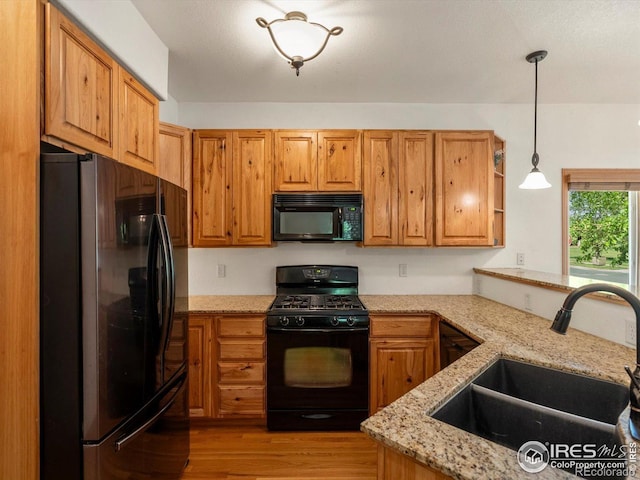 101 SE 2nd St, Berthoud, CO 80513 - kitchen with black appliances, a sink, light stone countertops, light wood finished floors, and decorative light fixtures