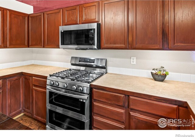 3255 Thundering Herd Way, Wellington, CO 80549 - kitchen featuring appliances with stainless steel finishes, light countertops, and brown cabinetry