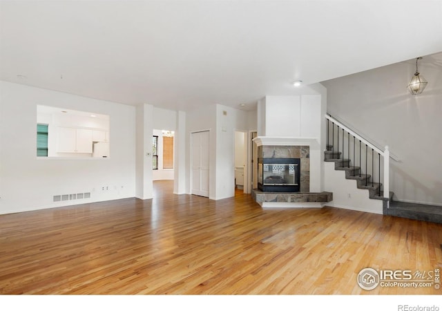 2982 W Long Dr # C, Littleton, CO 80120 - unfurnished living room featuring light wood-style flooring, a tile fireplace, and stairs