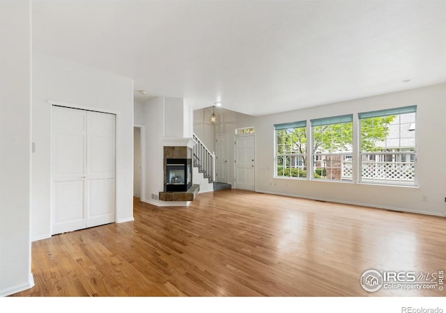 2982 W Long Dr # C, Littleton, CO 80120 - unfurnished living room featuring light wood-style flooring, a tiled fireplace, and baseboards