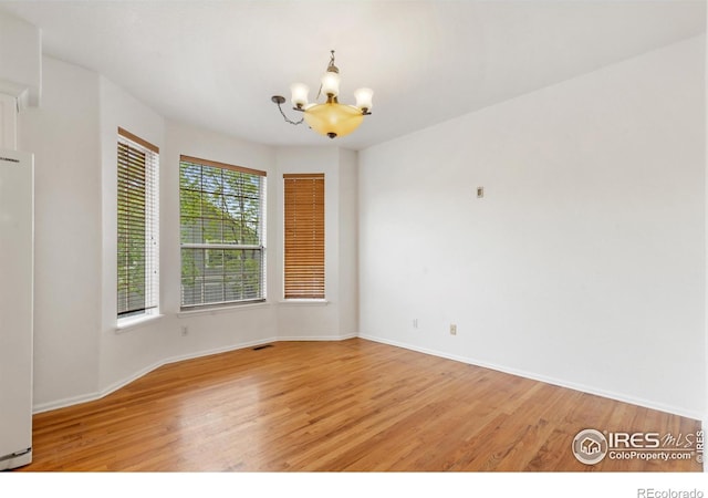 2982 W Long Dr # C, Littleton, CO 80120 - empty room featuring a chandelier, light wood-type flooring, and baseboards