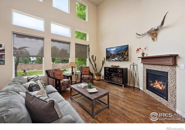 7401 Pimlico Dr, Windsor, CO 80550 - living area with wood finished floors, a tiled fireplace, baseboards, and a towering ceiling