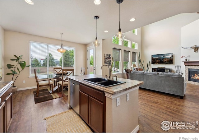 7401 Pimlico Dr, Windsor, CO 80550 - kitchen featuring a sink, dishwasher, dark wood finished floors, a glass covered fireplace, and decorative light fixtures