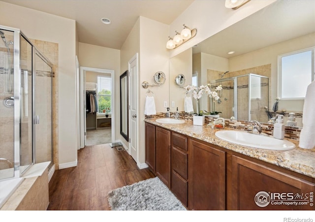 7401 Pimlico Dr, Windsor, CO 80550 - bathroom with a stall shower, wood finished floors, double vanity, a walk in closet, and baseboards