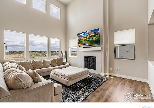 6398 Verna Ct, Timnath, CO 80547 - living room featuring a towering ceiling, baseboards, wood finished floors, and a fireplace