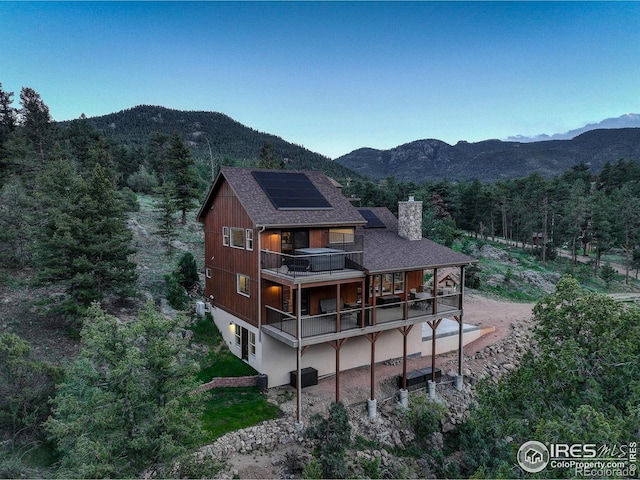 178 Cree Ct, Lyons, CO 80540 - rear view of house with solar panels, a balcony, a chimney, and a mountain view