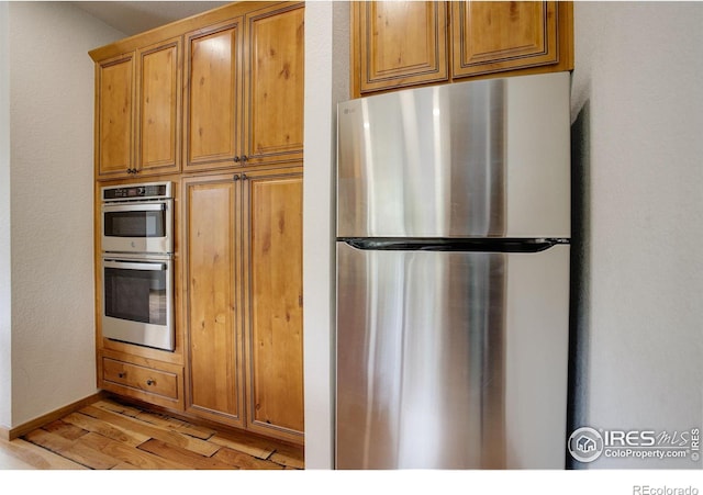 178 Cree Ct, Lyons, CO 80540 - kitchen featuring stainless steel appliances, light wood-style flooring, brown cabinets, and baseboards