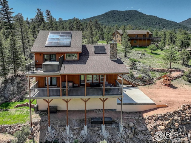 178 Cree Ct, Lyons, CO 80540 - back of house featuring solar panels, a mountain view, a balcony, and a chimney
