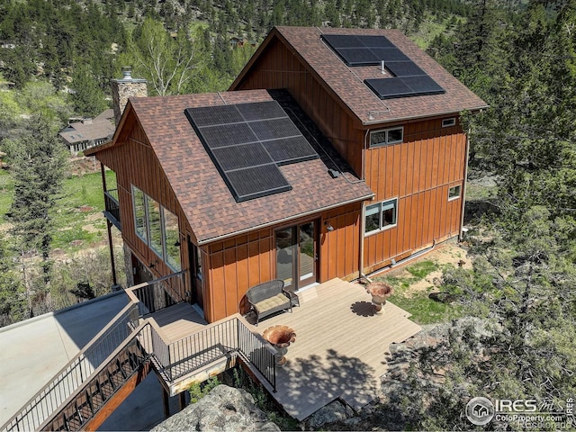 178 Cree Ct, Lyons, CO 80540 - rear view of property with a shingled roof, roof mounted solar panels, a chimney, and a wooden deck