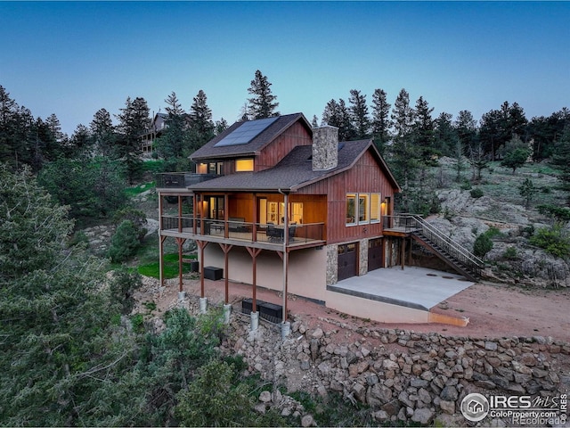 178 Cree Ct, Lyons, CO 80540 - rear view of house with roof mounted solar panels, a patio area, a chimney, a garage, and stairs