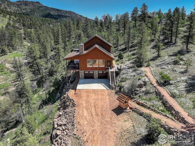 178 Cree Ct, Lyons, CO 80540 - view of front of home featuring a forest view, driveway, stone siding, a mountain view, and stairway