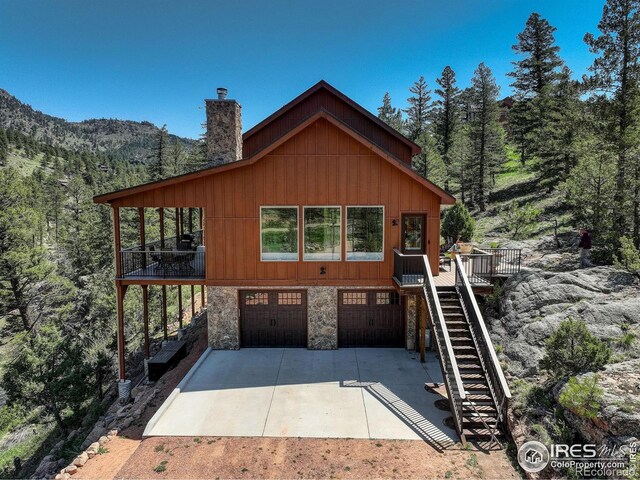 178 Cree Ct, Lyons, CO 80540 - rustic home with stairs, a garage, driveway, stone siding, and a chimney