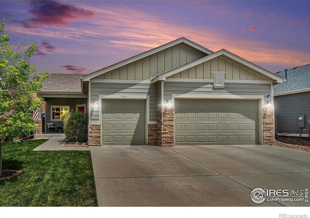 1040 Wagon Train Dr, Milliken, CO 80543 - view of front of home with stone siding, driveway, an attached garage, and a yard