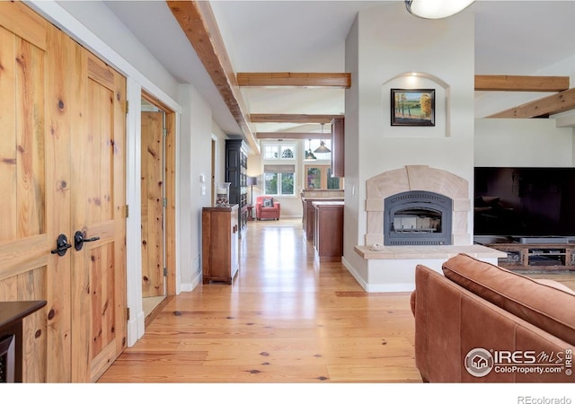 9445 Lykins Pl, Boulder, CO 80301 - living room featuring beam ceiling, light wood-style flooring, a glass covered fireplace, and baseboards