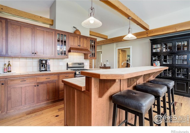 9445 Lykins Pl, Boulder, CO 80301 - kitchen featuring tile counters, stainless steel gas range oven, a kitchen bar, custom range hood, and beam ceiling