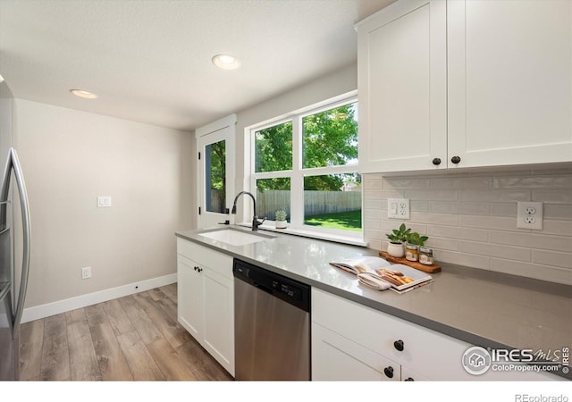 217 Locust St, Windsor, CO 80550 - kitchen with stainless steel appliances, a sink, decorative backsplash, light wood-type flooring, and white cabinetry