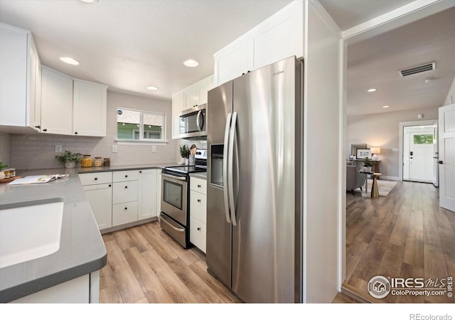 217 Locust St, Windsor, CO 80550 - kitchen featuring stainless steel appliances, light wood finished floors, white cabinets, backsplash, and recessed lighting