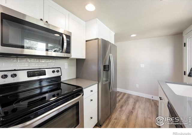 217 Locust St, Windsor, CO 80550 - kitchen featuring stainless steel appliances, a sink, light wood-style floors, white cabinets, and recessed lighting
