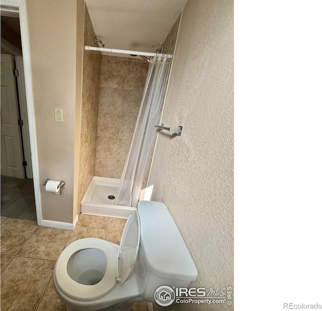 2614 Willard Dr, Colorado Springs, CO 80911 - full bathroom with a textured wall, a shower stall, toilet, and tile patterned flooring