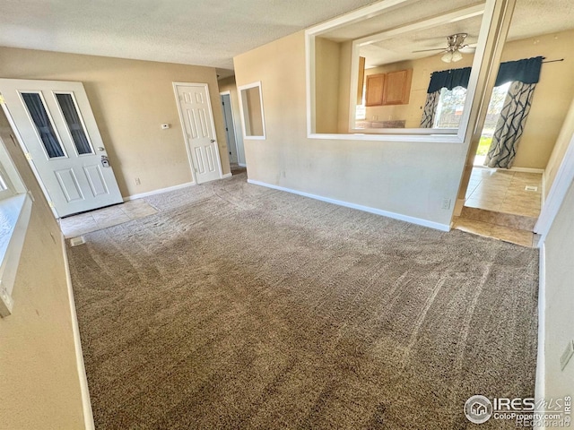 2614 Willard Dr, Colorado Springs, CO 80911 - unfurnished living room with carpet flooring, a textured ceiling, a ceiling fan, tile patterned floors, and baseboards