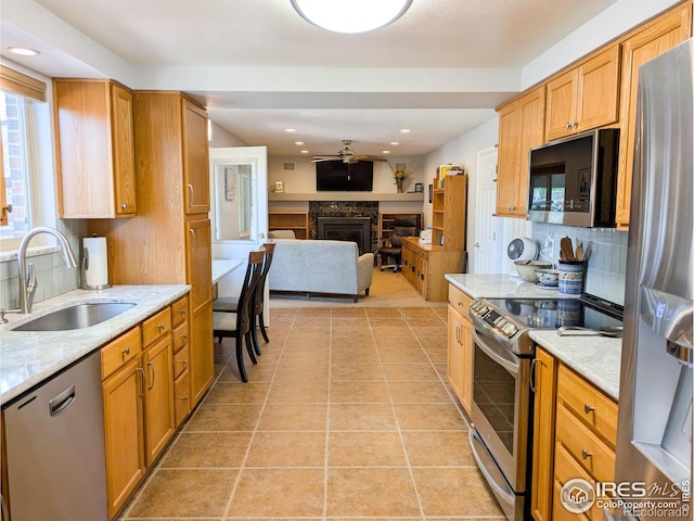 1545 S Vivian St, Longmont, CO 80501 - kitchen with stainless steel appliances, a sink, a fireplace, tasteful backsplash, and open floor plan
