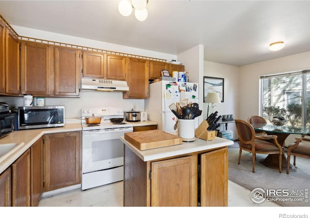 3465 Lochwood Dr Unit N62, Fort Collins, CO 80525 - kitchen featuring white appliances, under cabinet range hood, light countertops, brown cabinetry, and a kitchen island