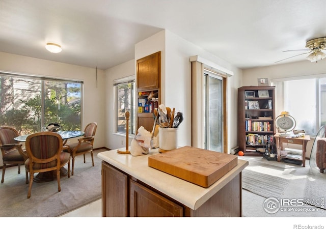 3465 Lochwood Dr Unit N62, Fort Collins, CO 80525 - kitchen with brown cabinets, light countertops, light colored carpet, a ceiling fan, and baseboard heating