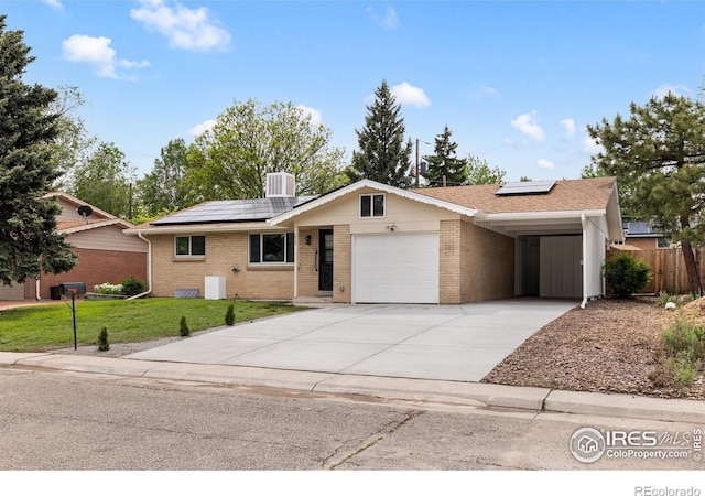 5329 Flower Cir, Arvada, CO 80002 - ranch-style home with roof mounted solar panels, brick siding, concrete driveway, and a garage
