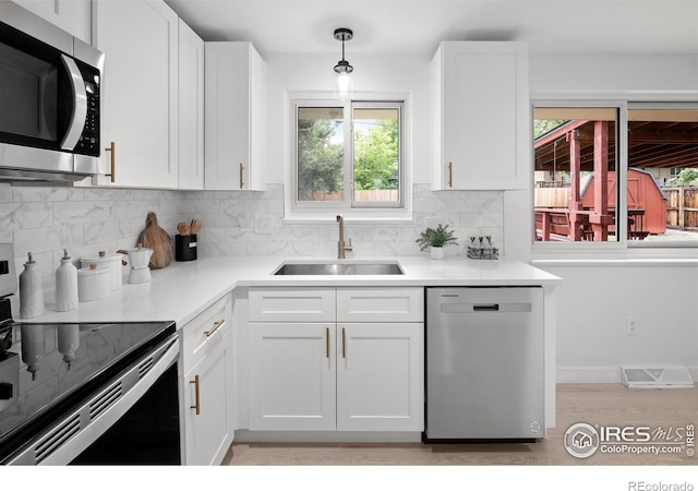 5329 Flower Cir, Arvada, CO 80002 - kitchen with stainless steel appliances, a sink, light wood-style floors, tasteful backsplash, and white cabinets