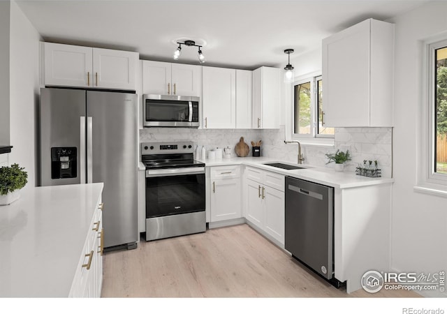 5329 Flower Cir, Arvada, CO 80002 - kitchen featuring stainless steel appliances, a sink, white cabinets, light wood-type flooring, and decorative backsplash