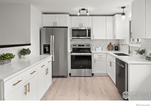 5329 Flower Cir, Arvada, CO 80002 - kitchen with appliances with stainless steel finishes, a sink, decorative backsplash, light wood finished floors, and white cabinetry