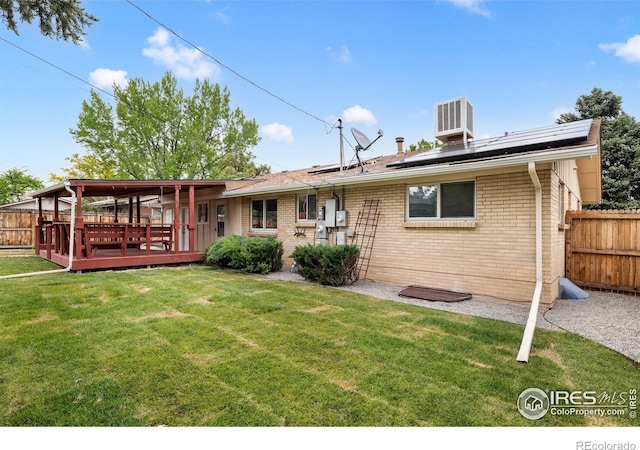 5329 Flower Cir, Arvada, CO 80002 - back of house featuring a wooden deck, brick siding, solar panels, and central AC