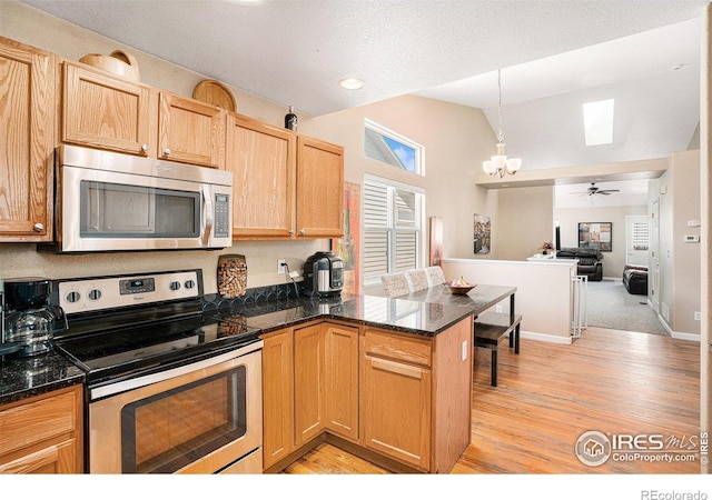 3525 Auntie Stone St Unit 7, Fort Collins, CO 80526 - kitchen with stainless steel appliances, a chandelier, vaulted ceiling, light wood-style flooring, and a peninsula