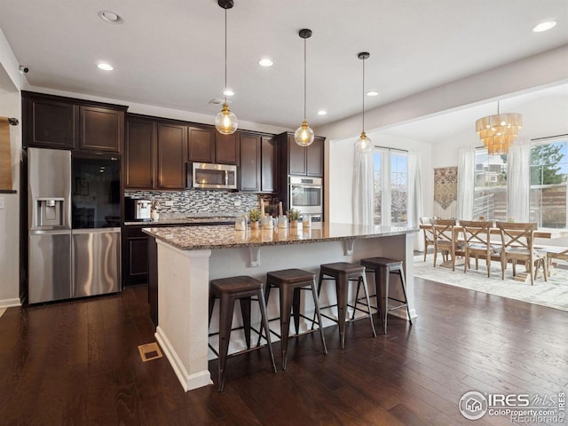 610 Sun Up Pl, Erie, CO 80516 - kitchen featuring appliances with stainless steel finishes, dark brown cabinets, dark wood-style floors, an island with sink, and recessed lighting