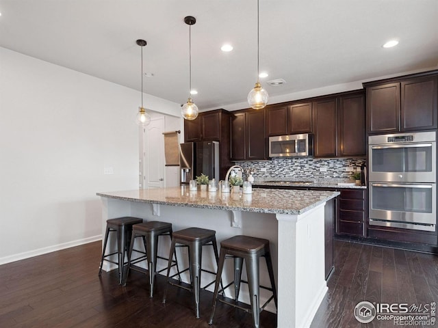 610 Sun Up Pl, Erie, CO 80516 - kitchen featuring appliances with stainless steel finishes, dark wood-type flooring, baseboards, dark brown cabinetry, and recessed lighting