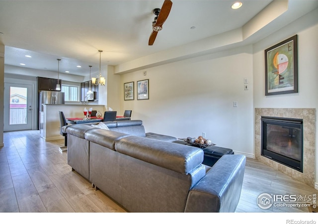 1240 Wren Ct Unit B, Longmont, CO 80501 - living area with light wood finished floors, a tiled fireplace, recessed lighting, ceiling fan, and a chandelier