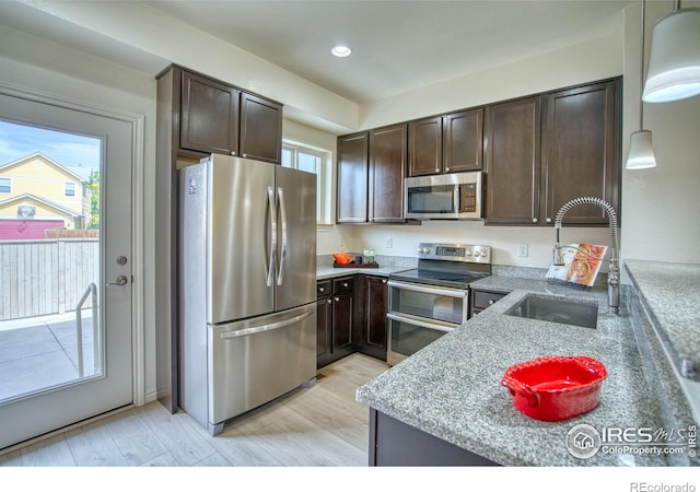 1240 Wren Ct Unit B, Longmont, CO 80501 - kitchen with appliances with stainless steel finishes, a sink, dark brown cabinetry, healthy amount of natural light, and recessed lighting