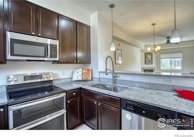 1240 Wren Ct Unit B, Longmont, CO 80501 - kitchen with appliances with stainless steel finishes, a sink, dark brown cabinetry, light stone countertops, and a fireplace