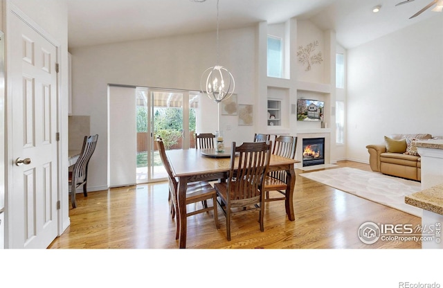 2139 Andrews St, Fort Collins, CO 80528 - dining space with light wood-style flooring, high vaulted ceiling, a fireplace with flush hearth, a chandelier, and baseboards