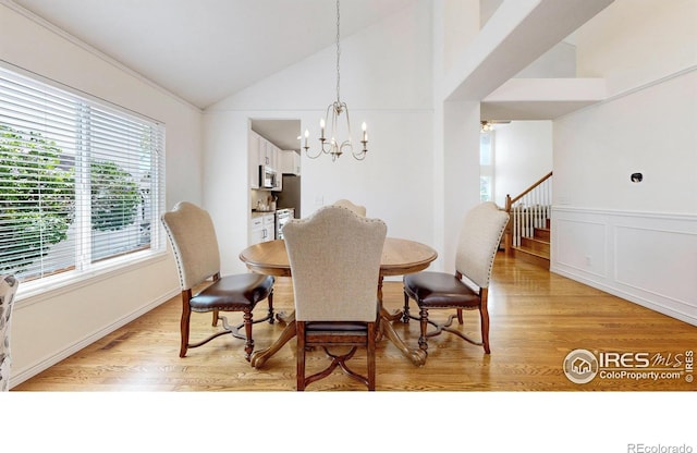 2139 Andrews St, Fort Collins, CO 80528 - dining area featuring light wood-style floors, vaulted ceiling, a chandelier, stairs, and a wainscoted wall