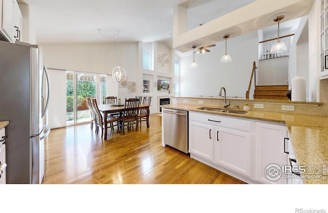 2139 Andrews St, Fort Collins, CO 80528 - kitchen featuring stainless steel appliances, a sink, light stone countertops, white cabinets, and high vaulted ceiling
