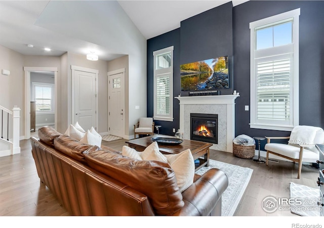 4268 Ardglass Ln, Timnath, CO 80547 - living room featuring a glass covered fireplace, wood finished floors, baseboards, lofted ceiling, and stairs