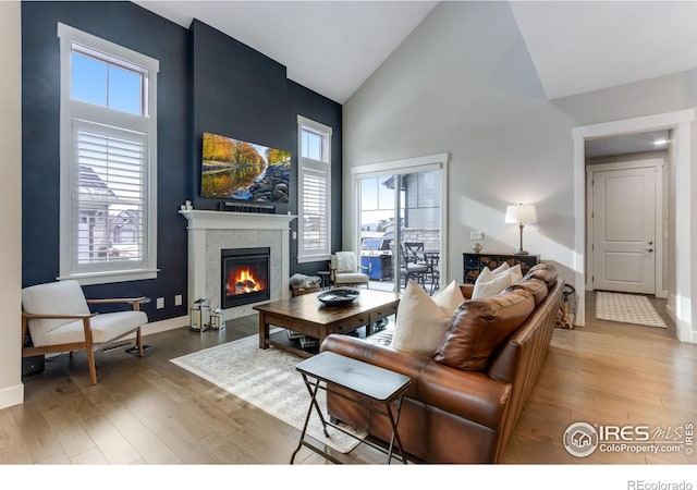 4268 Ardglass Ln, Timnath, CO 80547 - living room featuring high vaulted ceiling, wood finished floors, a lit fireplace, and baseboards