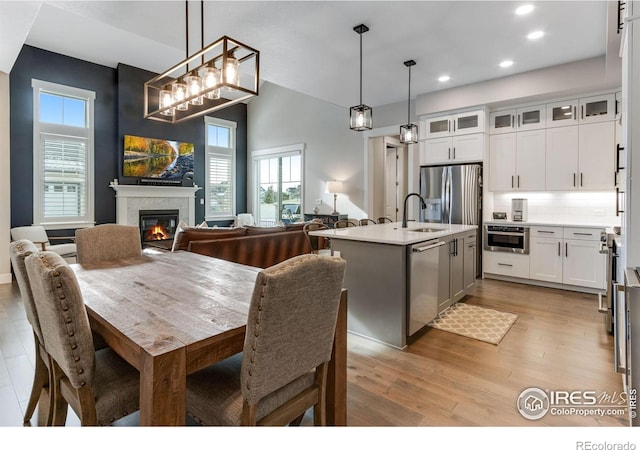 4268 Ardglass Ln, Timnath, CO 80547 - dining space featuring recessed lighting, light wood-style flooring, plenty of natural light, a glass covered fireplace, and a high ceiling