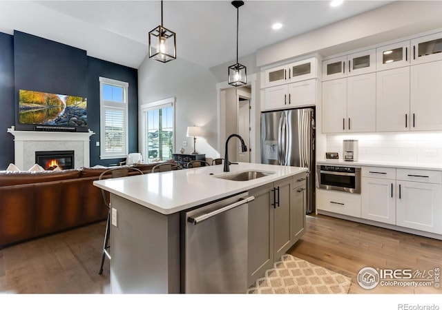 4268 Ardglass Ln, Timnath, CO 80547 - kitchen featuring appliances with stainless steel finishes, a sink, light countertops, backsplash, and light wood-type flooring