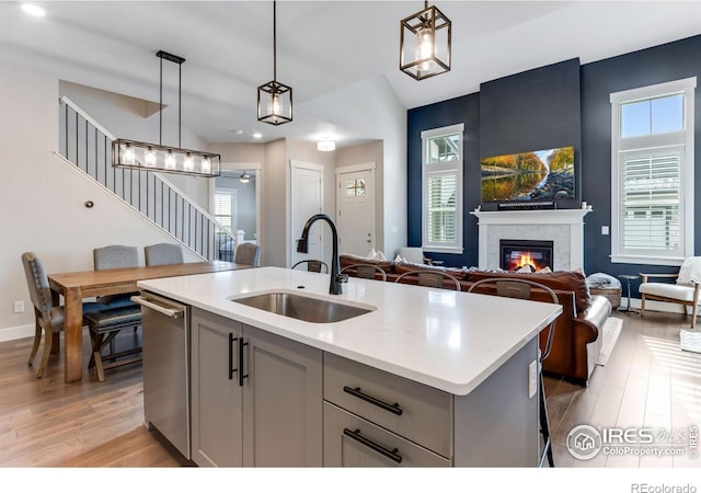4268 Ardglass Ln, Timnath, CO 80547 - kitchen featuring a sink, dishwasher, light wood-style floors, a glass covered fireplace, and gray cabinetry
