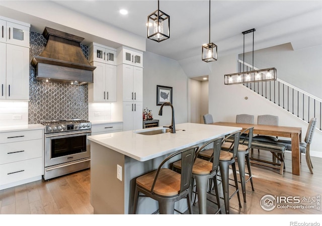 4268 Ardglass Ln, Timnath, CO 80547 - kitchen with stainless steel range, custom range hood, a sink, light wood-type flooring, and a center island with sink