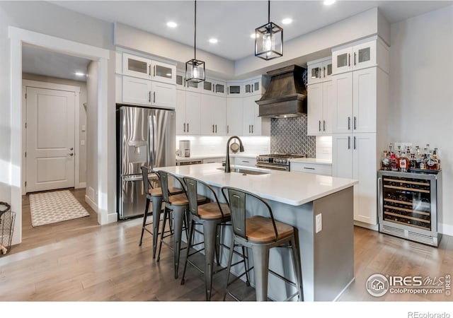 4268 Ardglass Ln, Timnath, CO 80547 - kitchen with stainless steel appliances, beverage cooler, premium range hood, a sink, and light wood finished floors