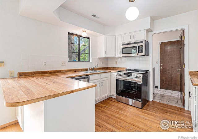 4116 W 111th Cir, Westminster, CO 80031 - kitchen with stainless steel appliances, a peninsula, white cabinets, and decorative backsplash