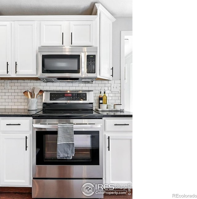 8290 Chase Way, Arvada, CO 80003 - kitchen with appliances with stainless steel finishes, dark countertops, white cabinets, and tasteful backsplash